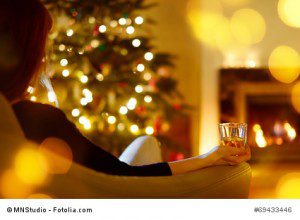 Woman with a drink by a fireplace on Christmas