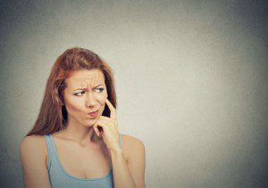 thoughtful skeptical suspicious young woman grey background