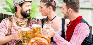 People with beer and pretzel in Bavarian inn eating and drinking