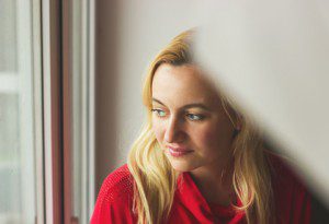 Toned portrait of Beautiful blonde woman sitting by the window.