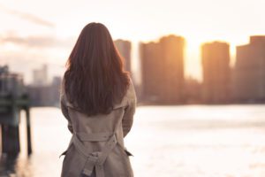 Beautiful lonely girl waiting for somebody bear the water at sunset time
