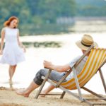 Mann im Liegestuhl schaut auf Frau, am See