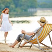 Mann im Liegestuhl schaut auf Frau, am See