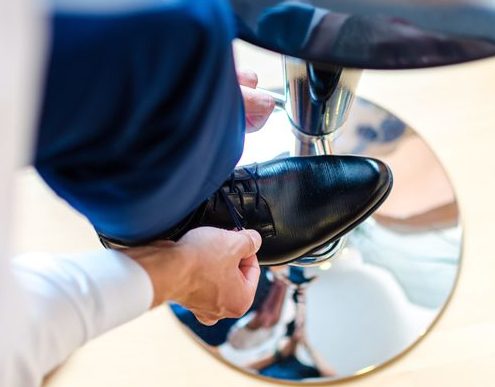 Mann mit Schuh auf Hocker