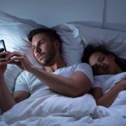 Man Using Cellphone While Her Wife Sitting On Bed